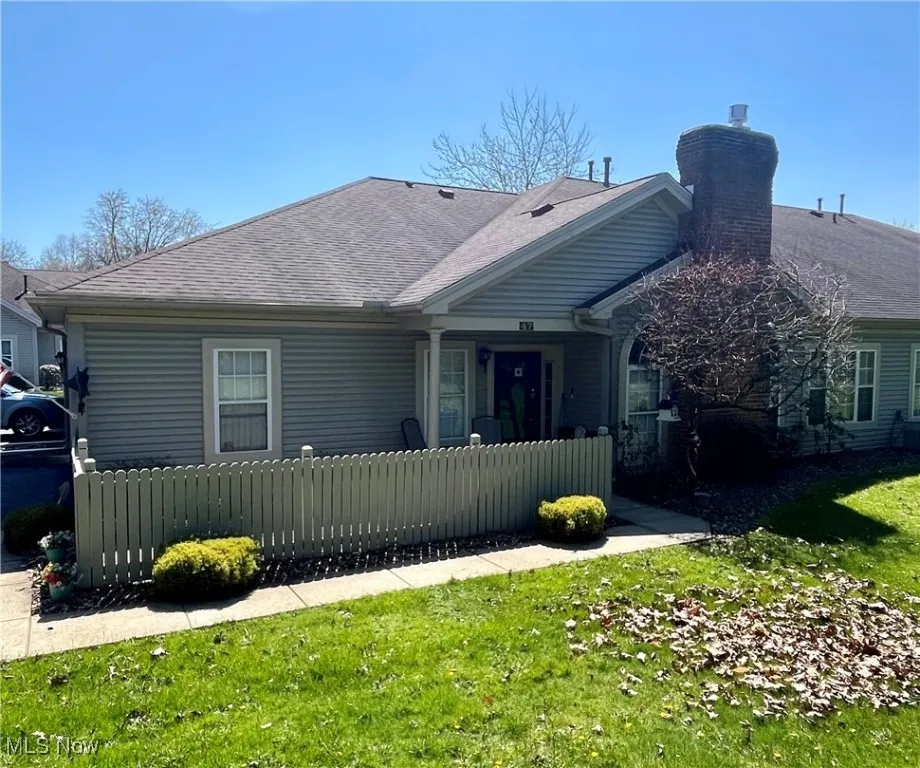 View of front of property with roof with shingles, a chimney, and a fenced front yard