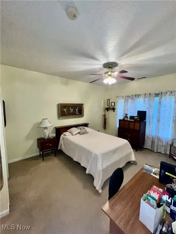 Bedroom featuring visible vents, baseboards, ceiling fan, a textured ceiling, and light carpet