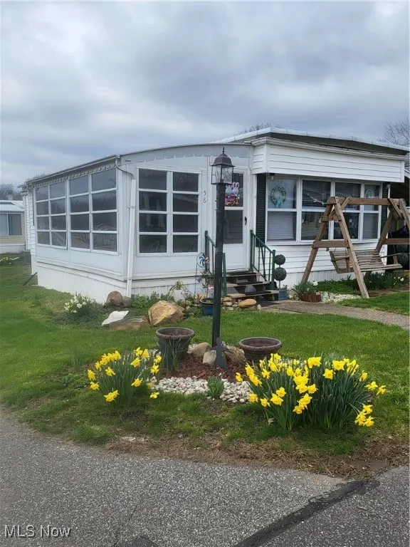 Manufactured / mobile home featuring entry steps and a front lawn
