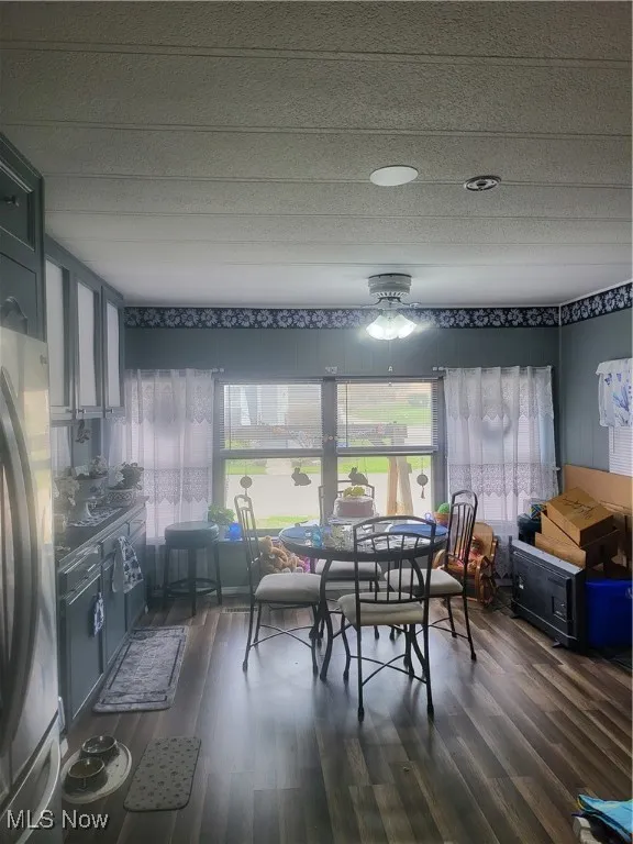 Dining space featuring ceiling fan and dark wood-style floors