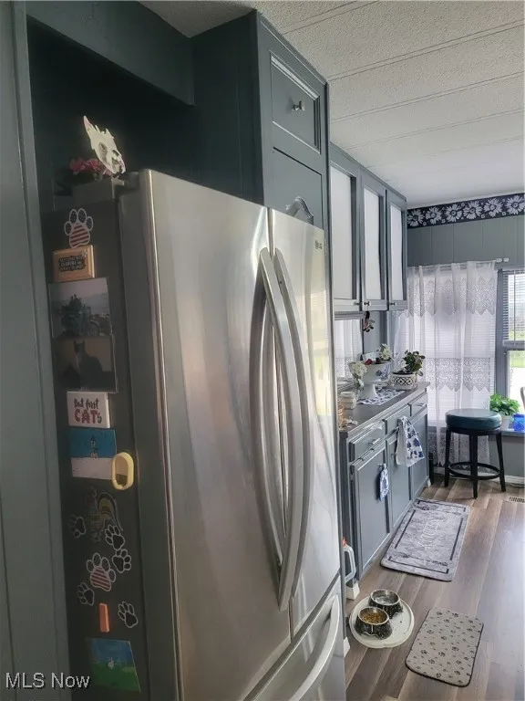 Kitchen with a textured ceiling, wood finished floors, and freestanding refrigerator