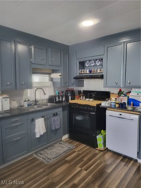 Kitchen featuring open shelves, dark wood finished floors, dishwashing machine, stove, and a sink