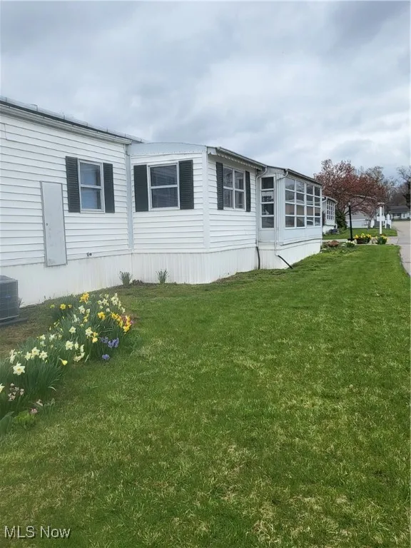 View of side of home featuring central air condition unit and a lawn