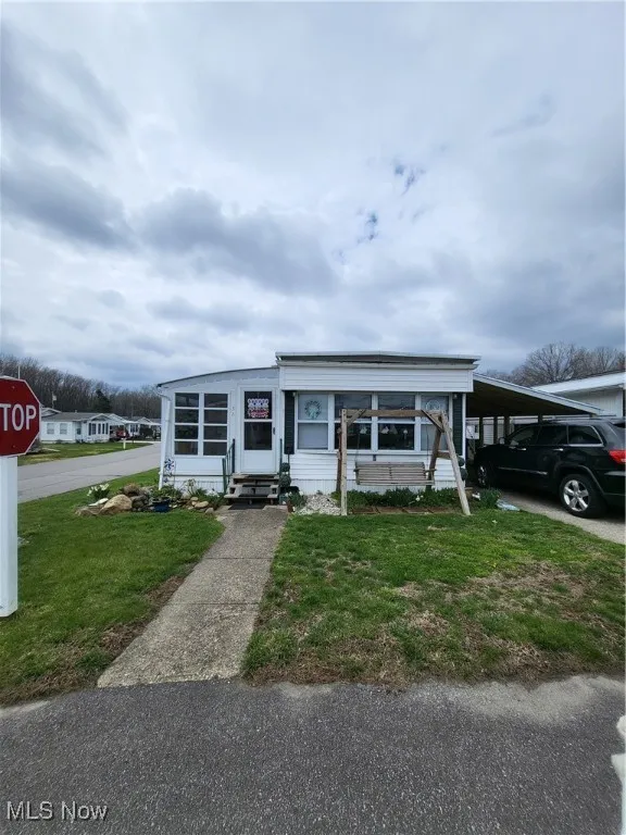 View of front of property with a carport, entry steps, and a front yard