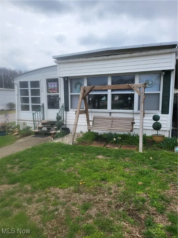 View of front of house with entry steps and a front yard