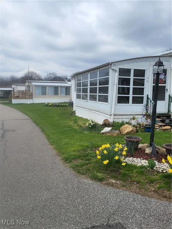 View of side of home with entry steps and a lawn