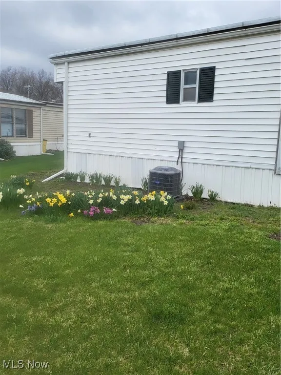 View of home's exterior featuring a yard and central air condition unit