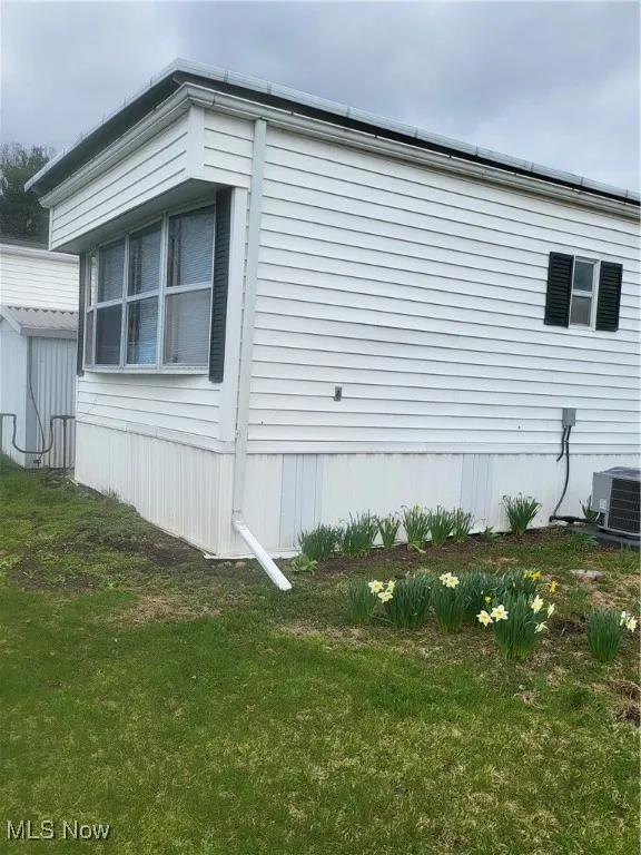 View of home's exterior with a yard and central AC