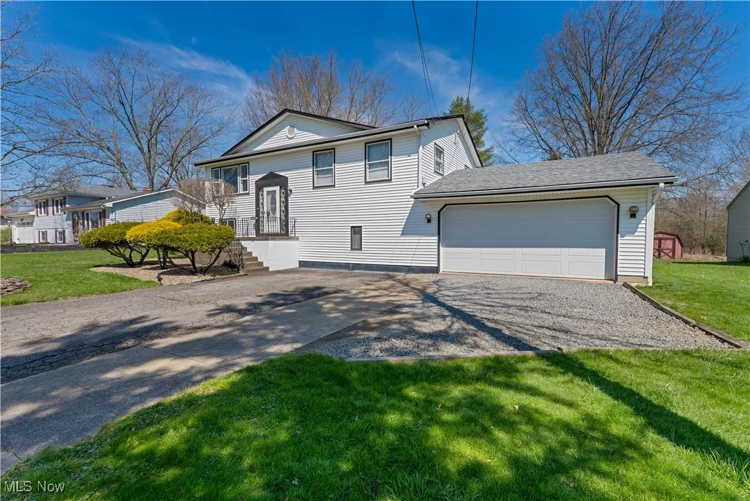 View of front of property with a front lawn, an attached garage, and driveway