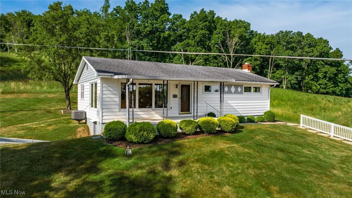 Ranch-style house featuring a front yard, a porch, a chimney, fence, and cooling unit