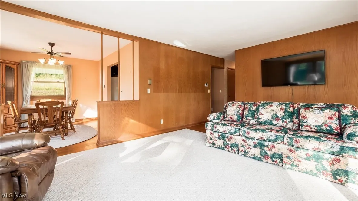 Living room featuring wooden walls and a ceiling fan