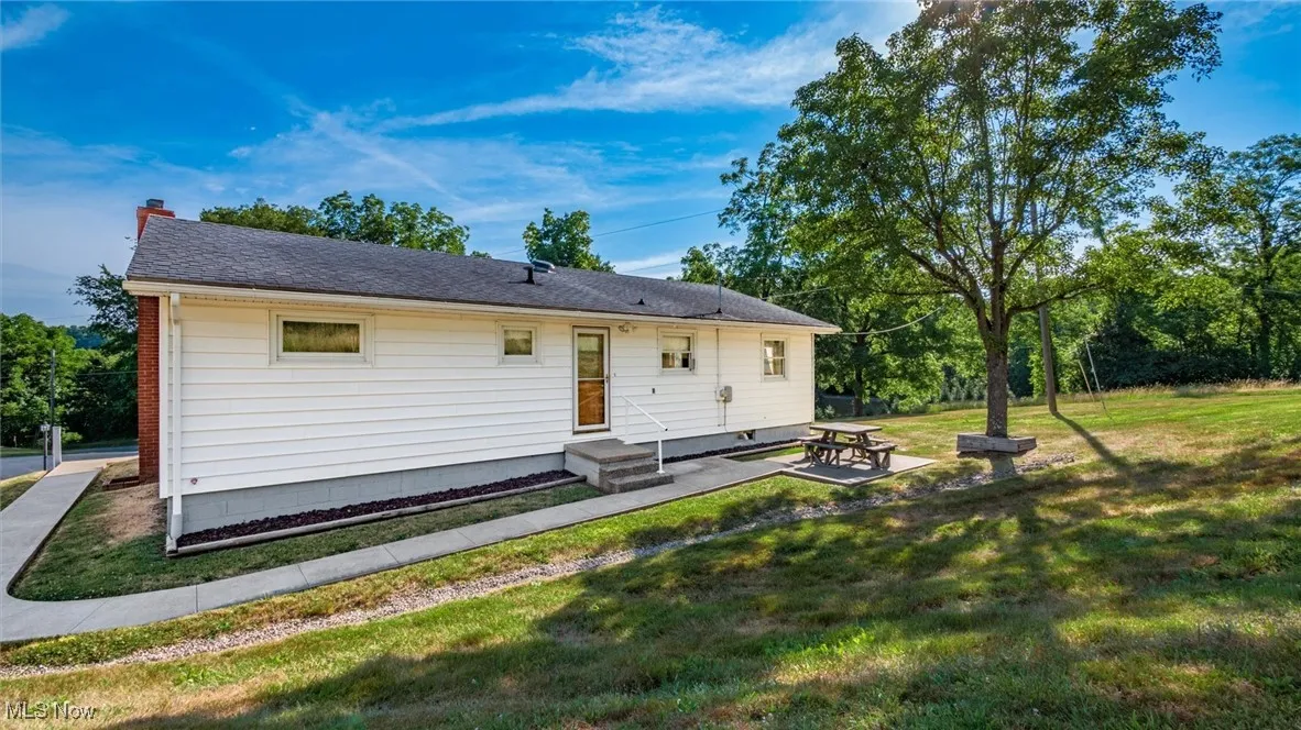 Back of property featuring a yard, roof with shingles, entry steps, and a chimney