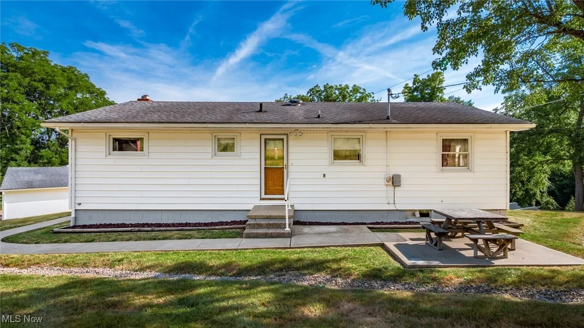 Back of property featuring a patio, a shingled roof, and a lawn