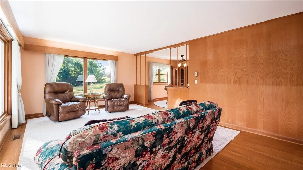 Living area featuring wood finished floors, wood walls, baseboards, and visible vents