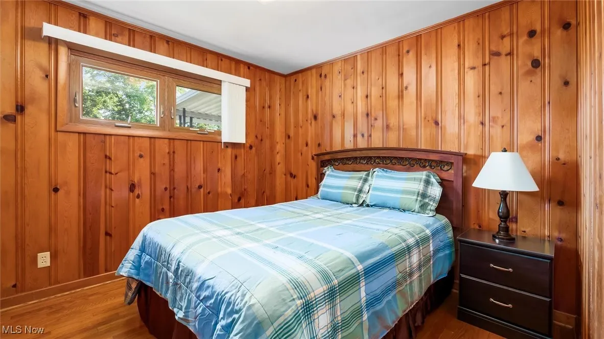 Bedroom featuring wooden walls, baseboards, and wood finished floors