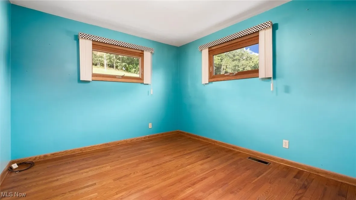 Spare room with visible vents, baseboards, and wood finished floors