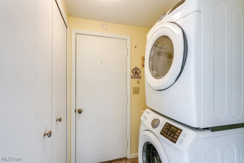 Washroom featuring stacked washing maching and dryer and laundry area