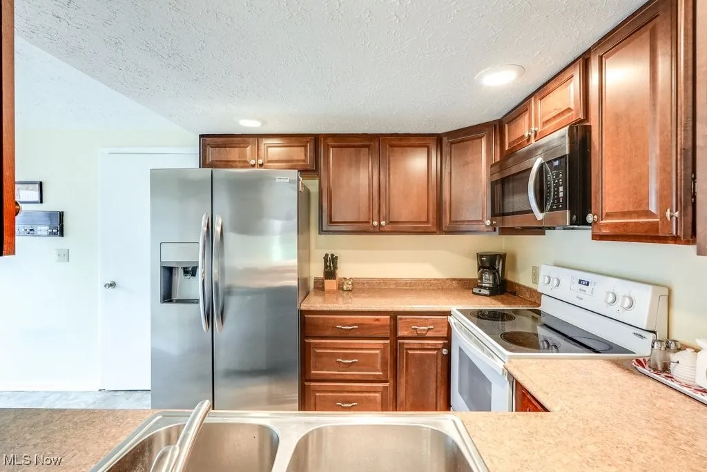 Kitchen featuring brown cabinets, light countertops, and stainless steel appliances