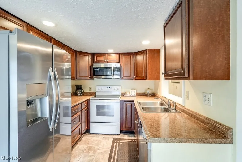 Kitchen featuring a sink, a textured ceiling, recessed lighting, and stainless steel appliances