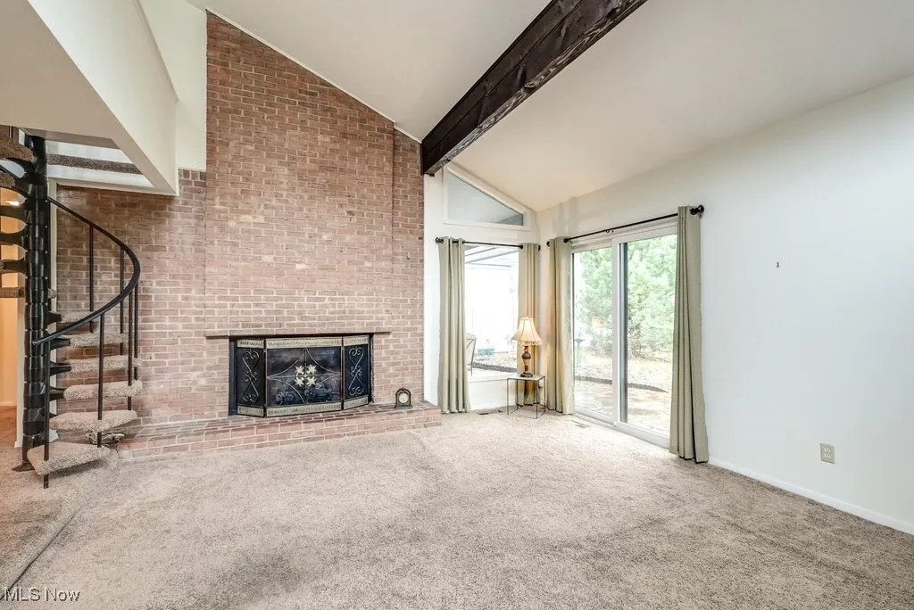 Unfurnished living room with high vaulted ceiling, a fireplace, carpet, stairs, and baseboards