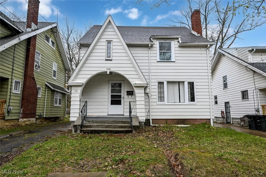 View of front facade featuring a porch, roof with shingles, a chimney, and a front yard