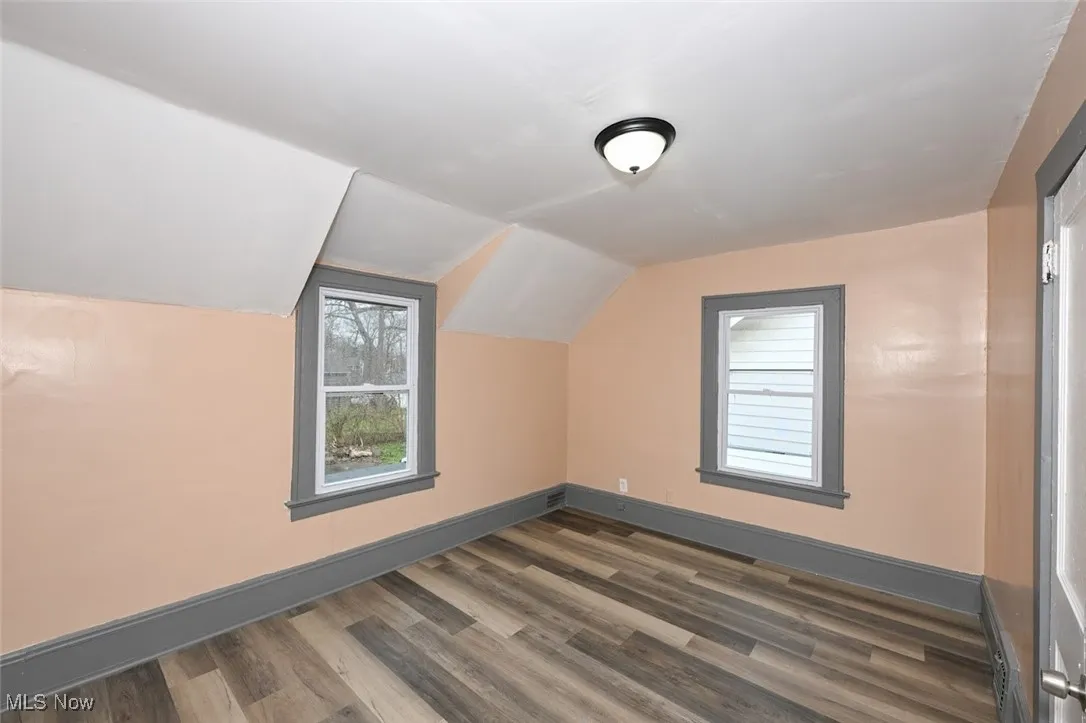 Additional living space featuring dark wood-style flooring, baseboards, and lofted ceiling