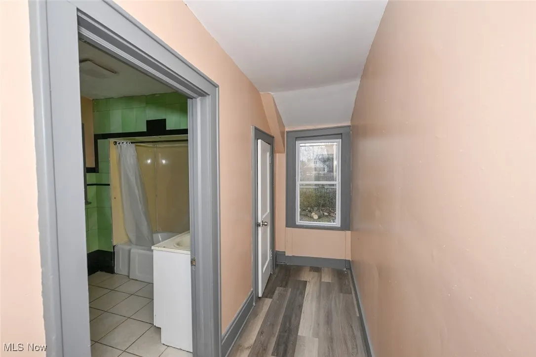 Hallway with washer / clothes dryer, light wood-style floors, and baseboards