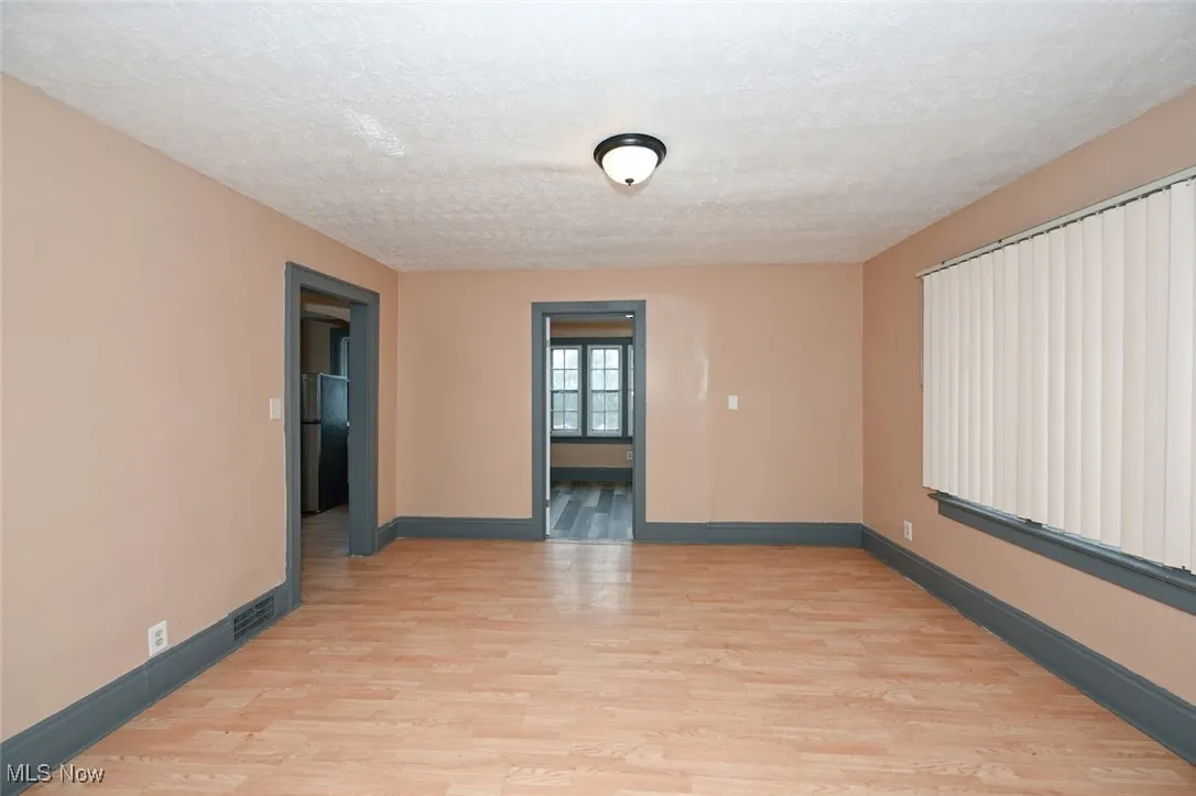 Unfurnished room with a textured ceiling, baseboards, visible vents, and light wood-style floors