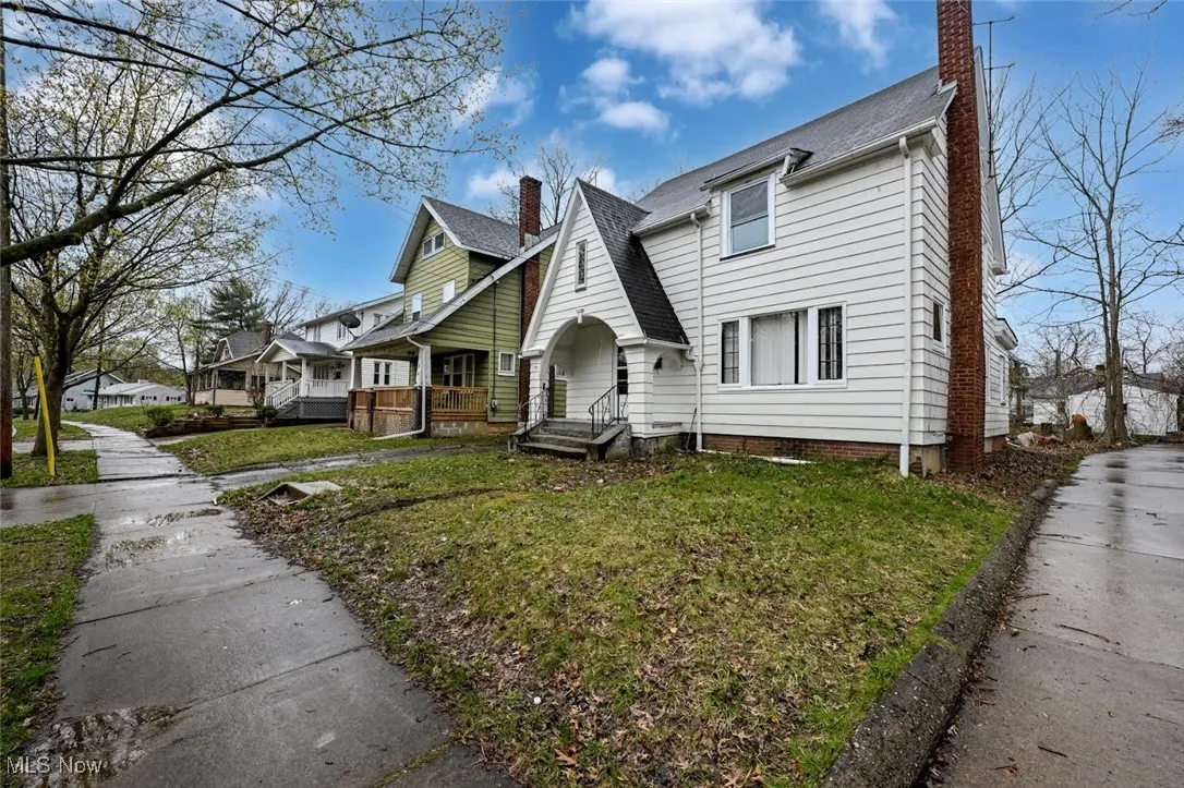 View of front of house with a residential view, roof with shingles, a chimney, and a front lawn