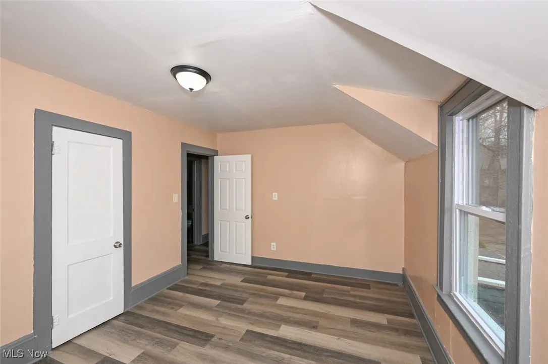Additional living space with wood finished floors, baseboards, and a healthy amount of sunlight