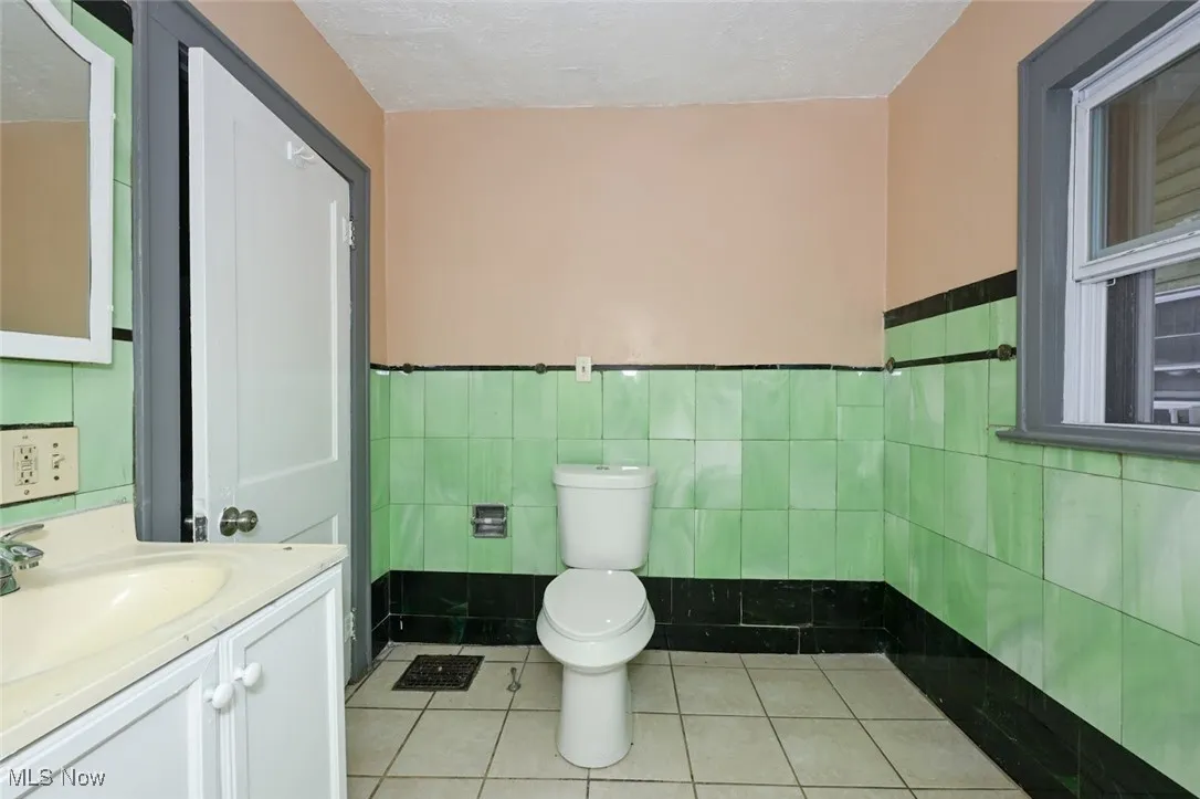 Bathroom featuring vanity, a wainscoted wall, toilet, tile walls, and tile patterned floors
