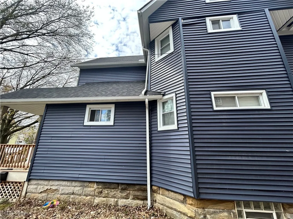 View of side of home with roof with shingles