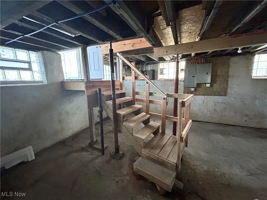 Below grade area with plenty of natural light, electric panel, and stairs