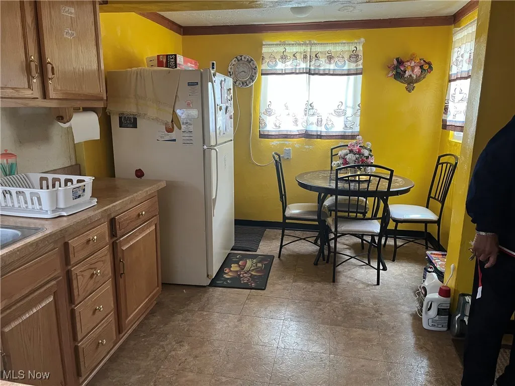 Kitchen with brown cabinetry and freestanding refrigerator