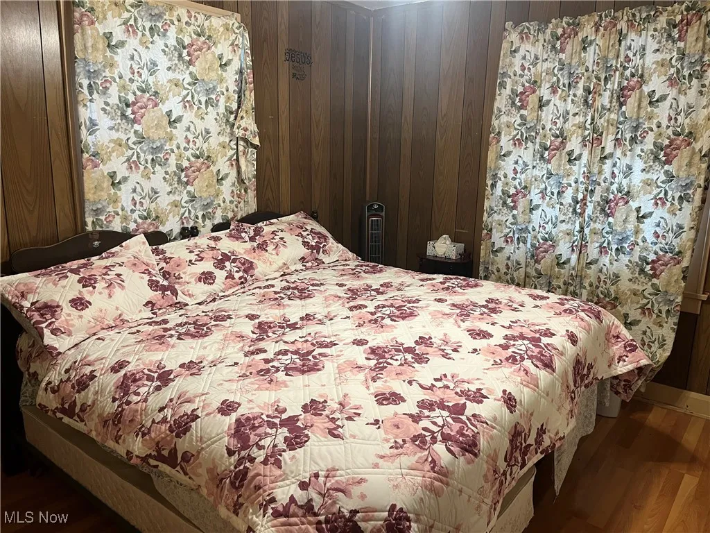 Bedroom featuring wooden walls and wood finished floors