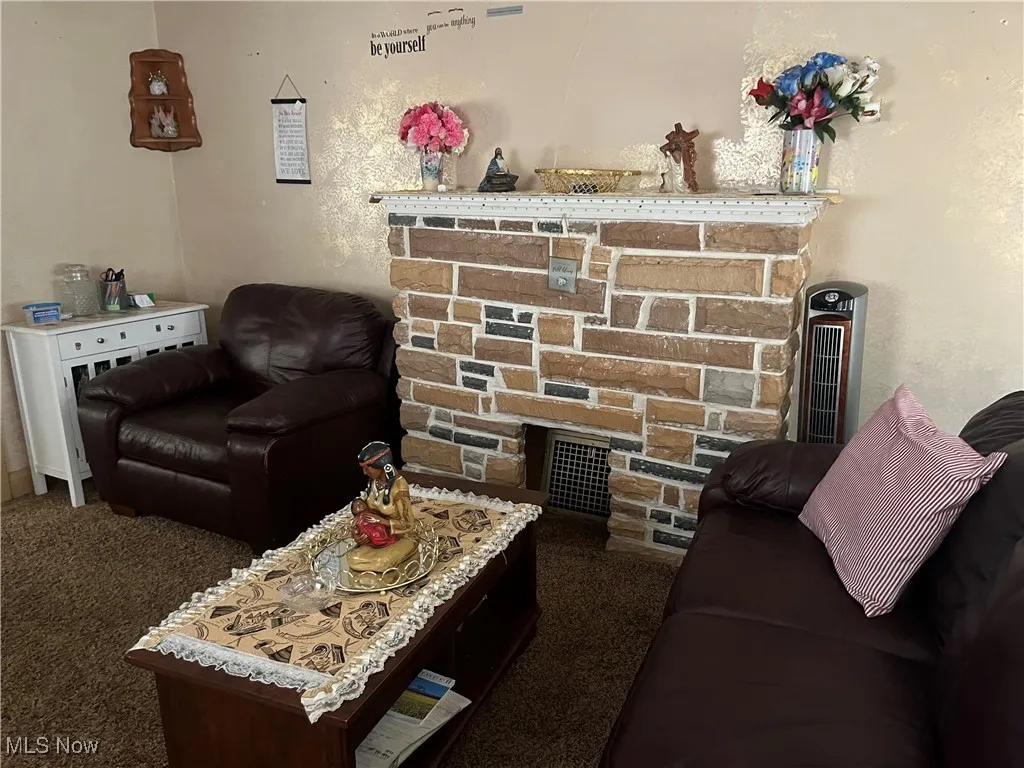 Carpeted living area featuring a stone fireplace