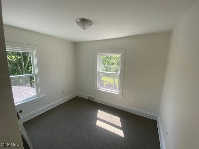 Spare room featuring baseboards and dark colored carpet