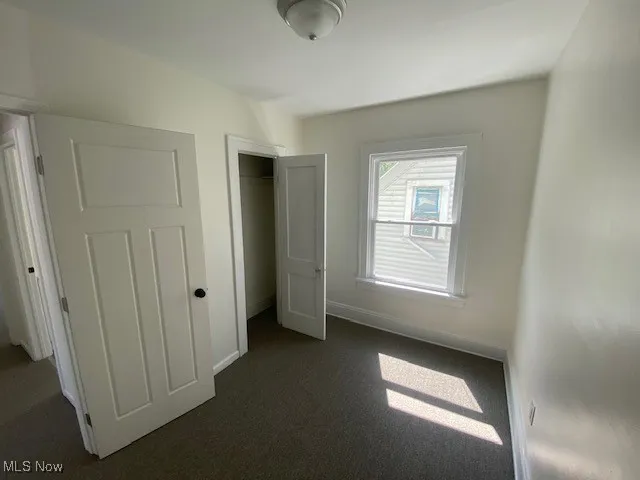 Unfurnished bedroom featuring dark carpet and a closet