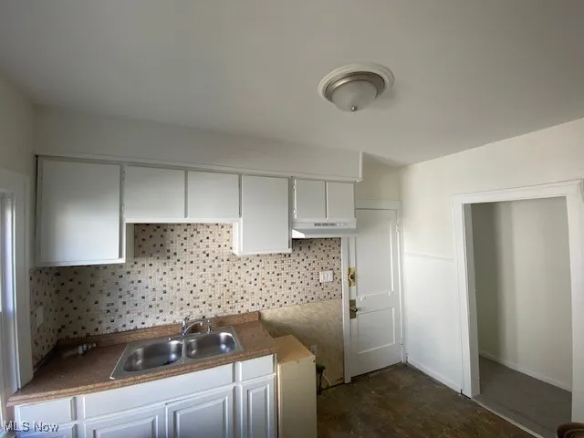 Kitchen featuring backsplash, white cabinetry, and under cabinet range hood