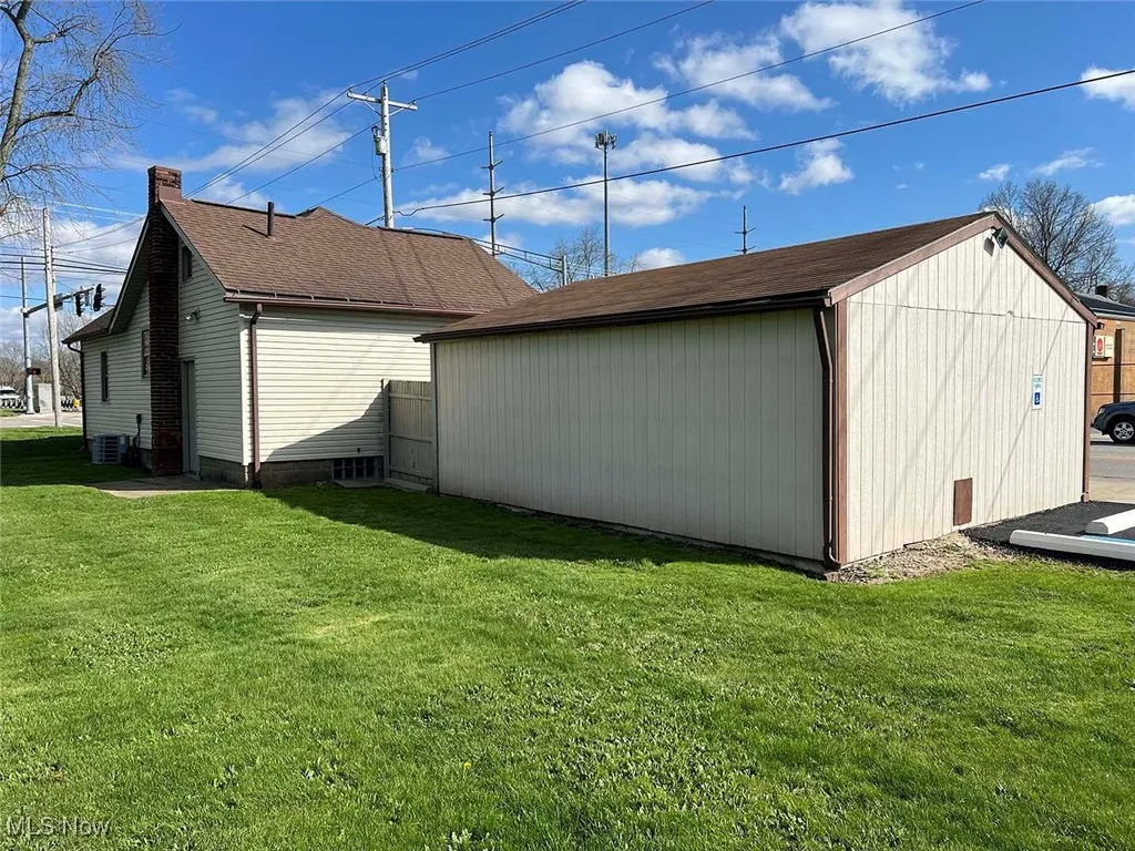 View of property exterior featuring an outbuilding, central AC, a chimney, a lawn, and a shed