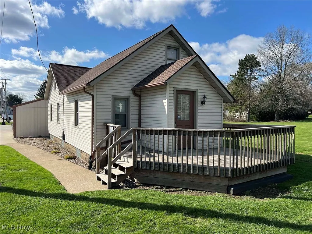 Front of property with a wooden deck, a yard, and a shingled roof