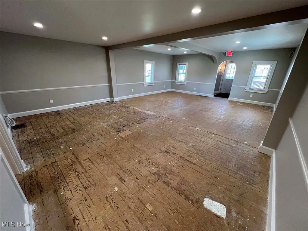 Unfurnished room with hardwood / wood-style flooring, baseboards, arched walkways, and recessed lighting