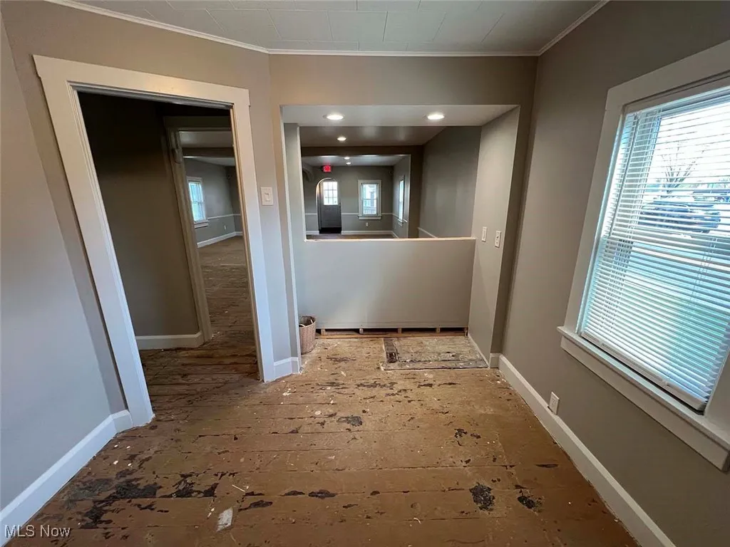 Hallway with crown molding and baseboards