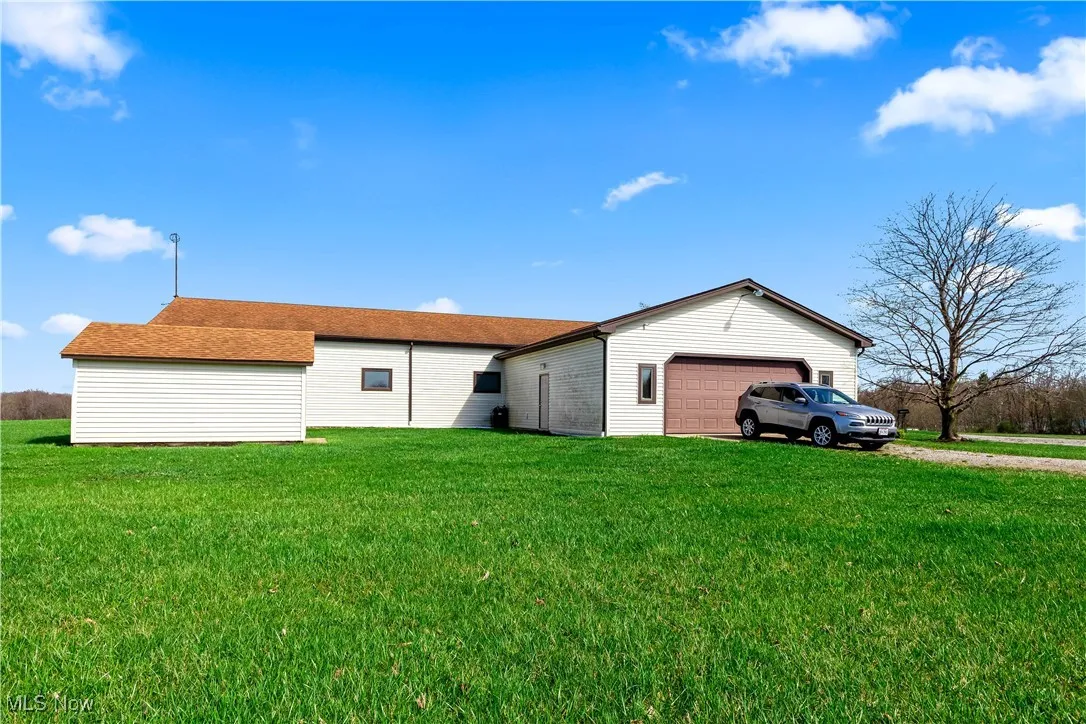 Rear view of property with an attached garage, a yard, and driveway