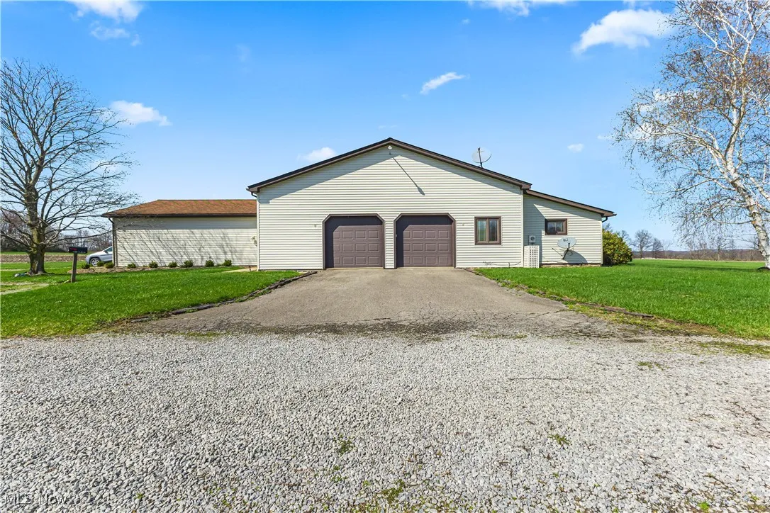 View of back of property with an attached garage, a lawn, and driveway
