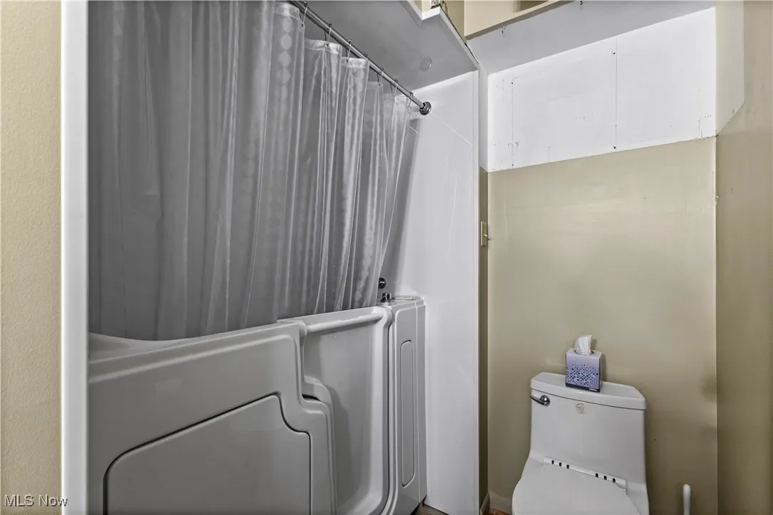 Full bathroom with toilet and shower / bath combo with shower curtain