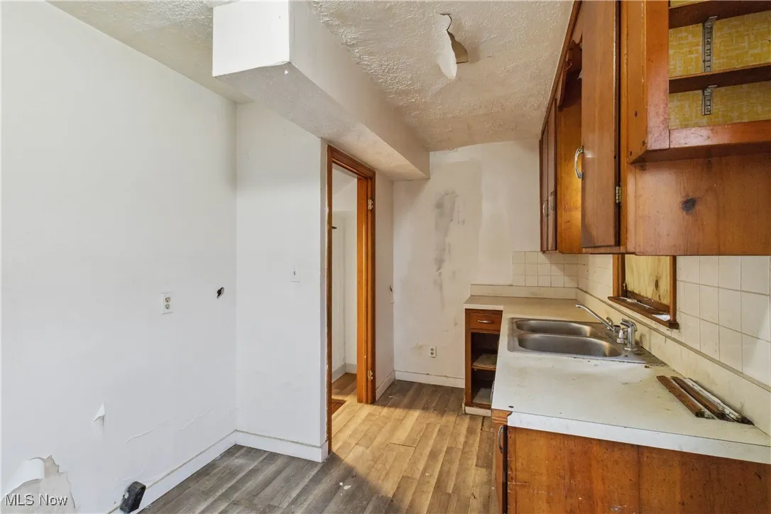Kitchen featuring brown cabinetry, light countertops, a sink, and tasteful backsplash