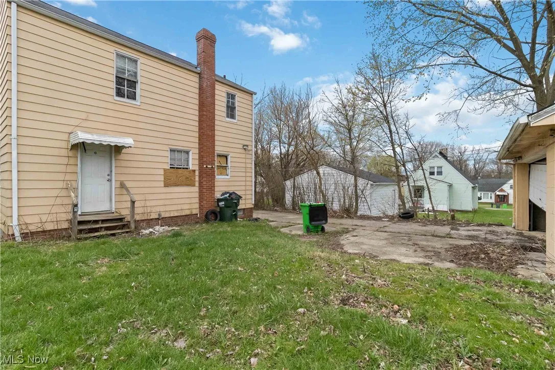 Back of property featuring a lawn, a chimney, and entry steps