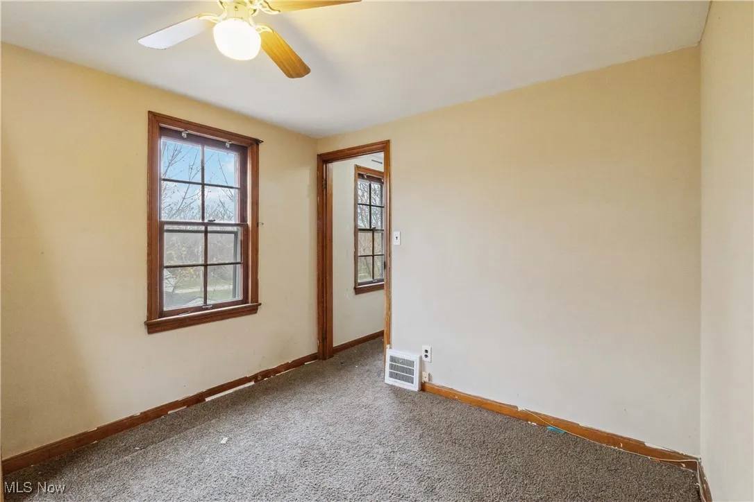 Carpeted empty room featuring visible vents, baseboards, and ceiling fan