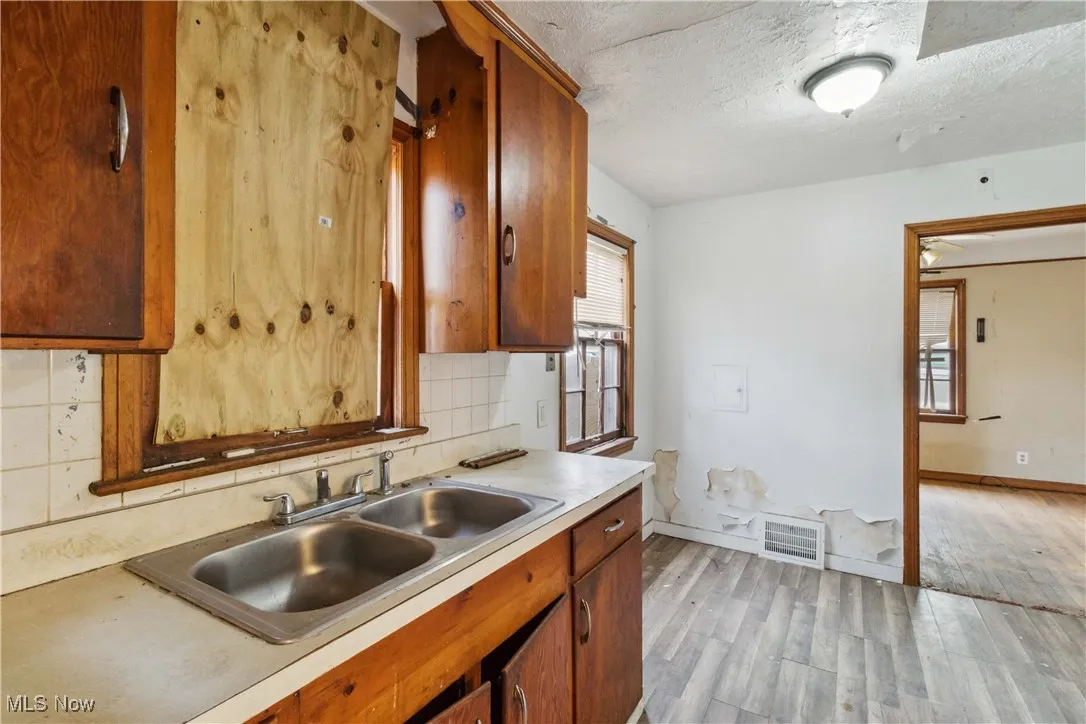 Kitchen with light countertops, visible vents, a sink, light wood-style floors, and tasteful backsplash